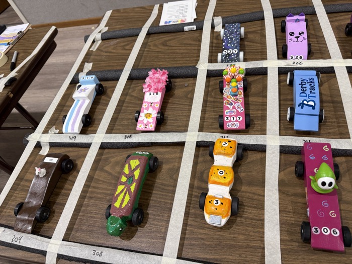 Handmade derby cars decorated with candy, flowers, and colorful characters.